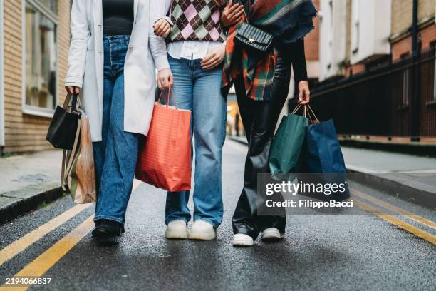 three young women walking down the street after shopping spree - fashionable stock pictures, royalty-free photos & images