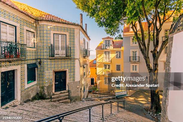 street with tile decorated residential houses in alfama district, lisbon, portugal - lissabon stockfoto's en -beelden