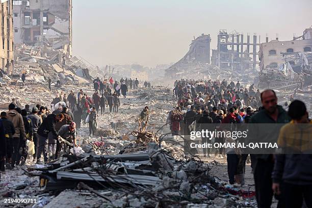 Scores of displaced Palestinians walk along a road in the Saftawi area of Jabalia, as they leave areas near Gaza City where they had taken refuge,...