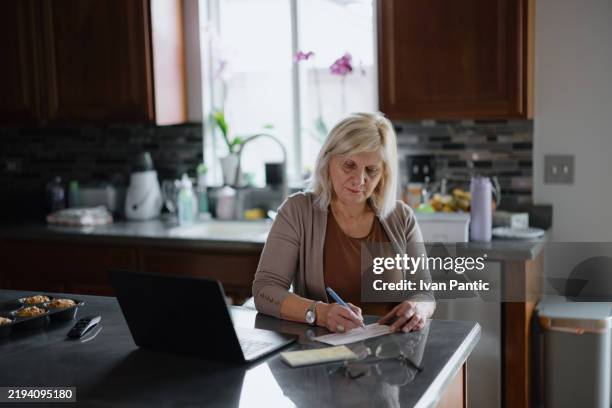 woman working on papers in a home kitchen environment - to do list stock pictures, royalty-free photos & images