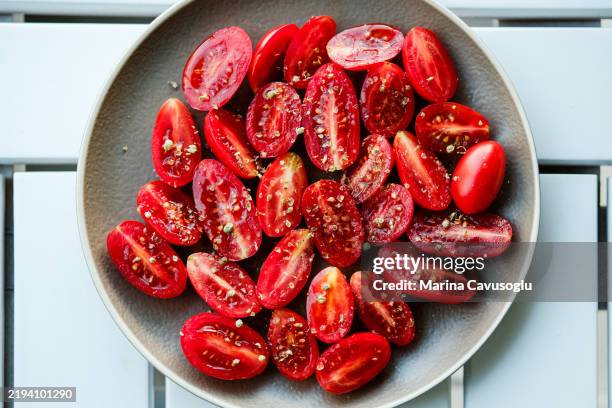 cut cherry tomatoes on a plate. - cherry tomato stock pictures, royalty-free photos & images