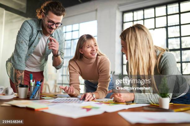 team von glücklichen freiberuflern, die über pläne im büro sprechen. - grafiker stock-fotos und bilder