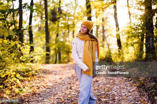 girl in scarf and hat walking in forest - alleen één tienermeisje stockfoto's en -beelden