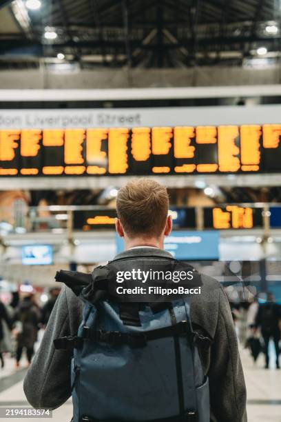 touriste regardant le tableau des départs à la gare de londres liverpool street - gare ferroviaire photos et images de collection