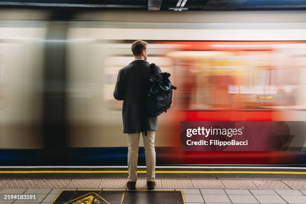 businessman waiting for the tube train at the london underground station - built structure stock pictures, royalty-free photos & images