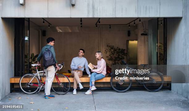 group of friends socializing at a cafe with their bicycles - mannelijke vriendschap stockfoto's en -beelden