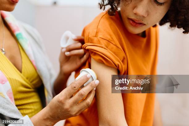 mom gently attaching a diabetes monitoring device to her kid - continuous glucose monitor stock pictures, royalty-free photos & images