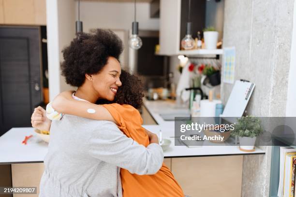 mother and son hugging in the kitchen - continuous glucose monitor stock pictures, royalty-free photos & images