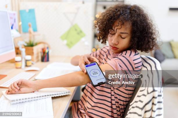 teenager using an app to check his sugar level - glucose stockfoto's en -beelden