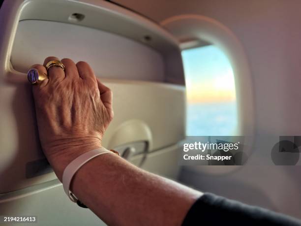 close-up of a nervous woman's outstretched arm holding the back of an airplane seat - affolé photos et images de collection