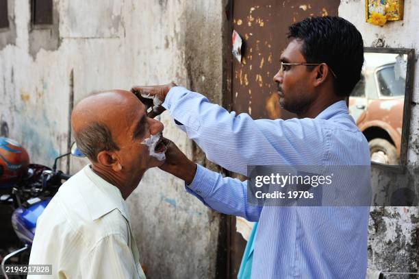 roadside barber shop in downtown mumbai, maharashtra state, india. in india, most people choose the cheapest way to have their hair cut. - shaved head stock pictures, royalty-free photos & images