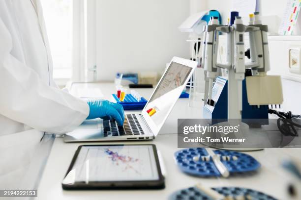 close-up shot of scientists hands typing data in laptop in laboratory - équipement de laboratoire photos et images de collection