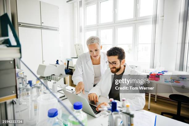 two scientists collaborating on research using a laptop in a laboratory - microbiologie photos et images de collection