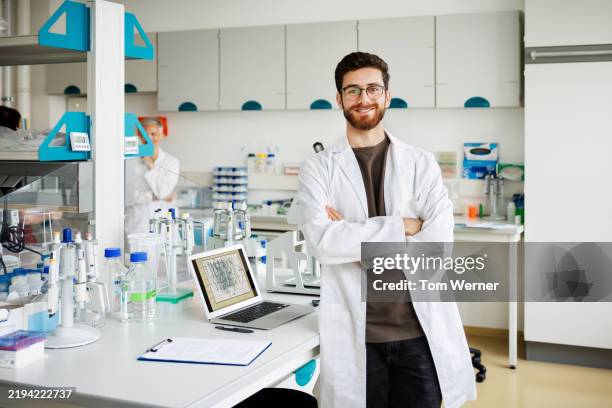 confident male scientist standing in a high-tech research laboratory - laborkittel stock-fotos und bilder