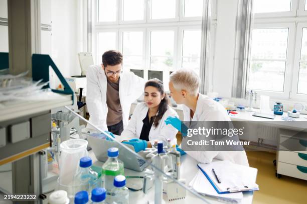 three scientists collaborating around a computer in a modern laboratory - usability lab stock pictures, royalty-free photos & images