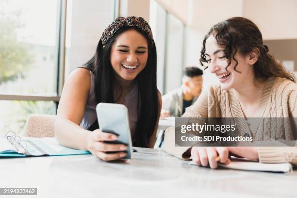 two happy high school girls using a smartphone together - high school america stock pictures, royalty-free photos & images