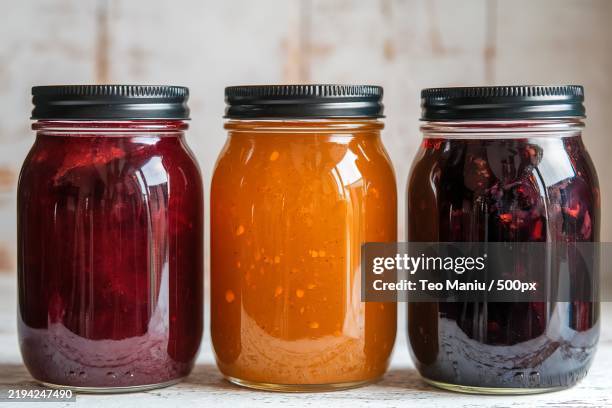 a photo of three glass jars standing side by side with a jam - marmelade stock-fotos und bilder