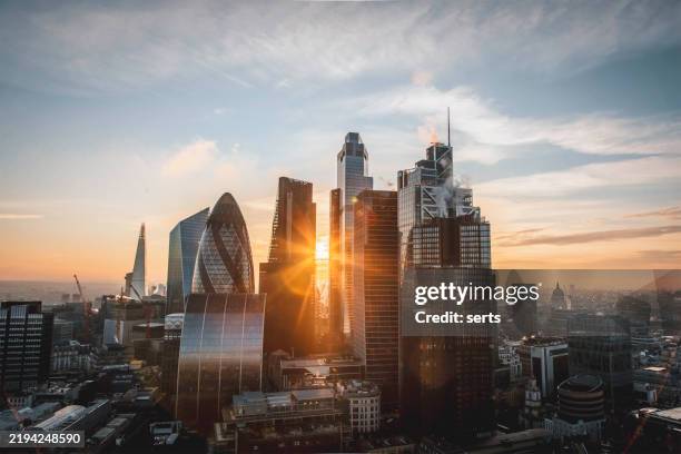 sunlight glowing through skyscrapers in london, england, uk - city of london stockfoto's en -beelden