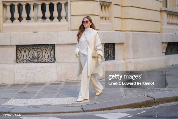 Diane Batoukina wears brown Dior sunglasses, a white cashmere Zara turtleneck pullover, matching coat and pants, a light brown fluffy faux fur Prada...