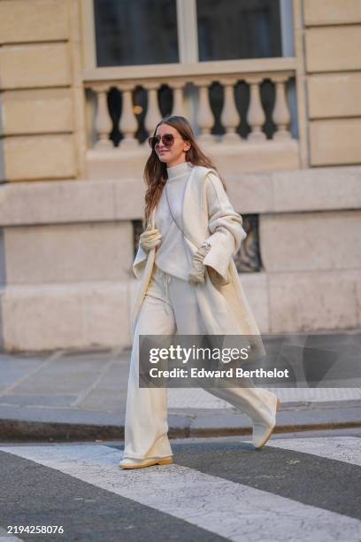 Diane Batoukina wears brown Dior sunglasses, a white cashmere Zara turtleneck pullover, matching coat and pants, a light brown fluffy faux fur Prada...