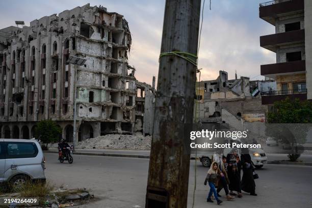 Syrians walk amid civil war ruins, as they mark the rebel victory in a rebel stronghold city that was besieged from 2011 to 2014 on December 16, 2024...
