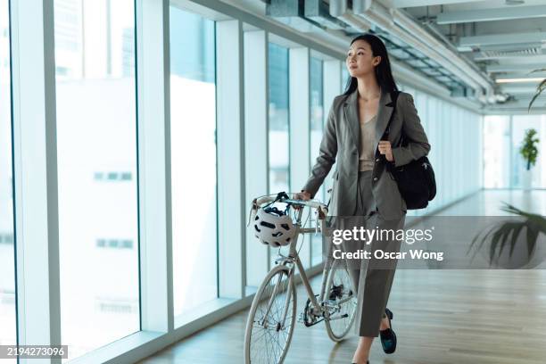 young asian businesswoman arriving to work on bike - workplace wellbeing stock pictures, royalty-free photos & images
