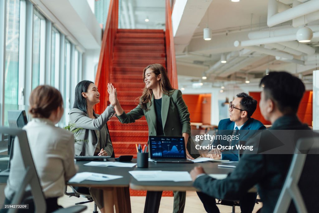 Cheerful Asian female business manager giving a speech to motivate her team in a modern office