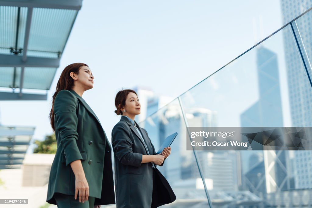 Two confident Asian businesswoman looking at corporate skyscrapers