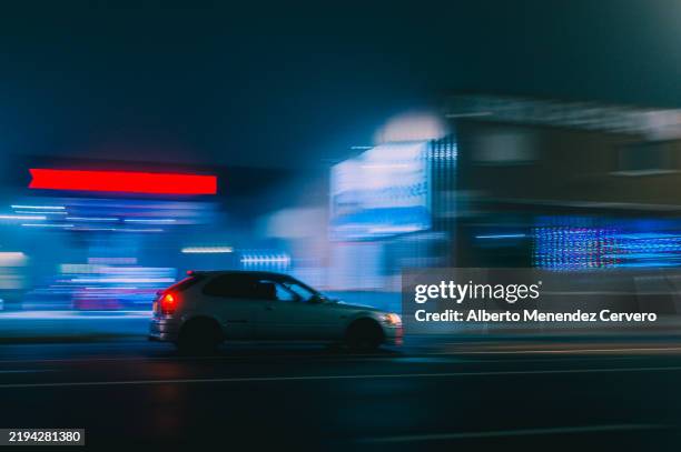racing car passing by gas station at night with motion blur - chasing stock pictures, royalty-free photos & images