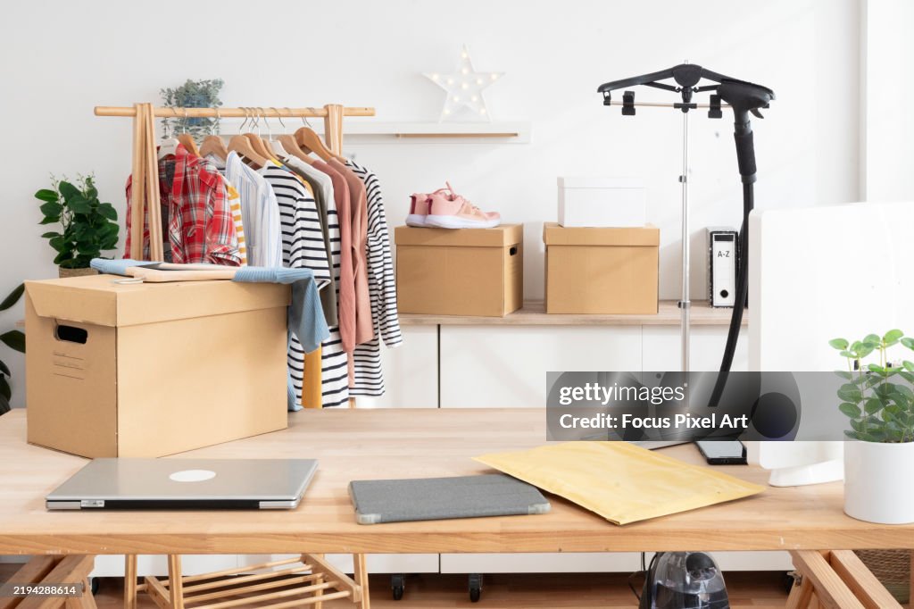Clothes hanging on a rack and cardboard boxes in a small e-commerce business, getting ready for shipping