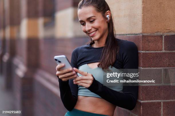 mujer comprobando la aplicación de fitness después de la carrera - corredora de footing fotografías e imágenes de stock