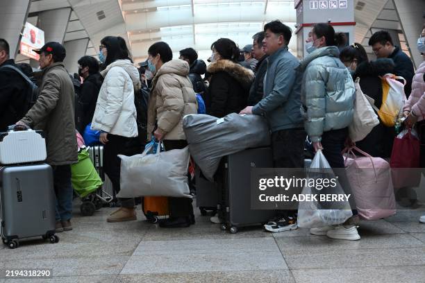 People queue to board trains as they return to their hometowns for the Chinese Lunar New Year reunions at a train station in Beijing on January 20,...