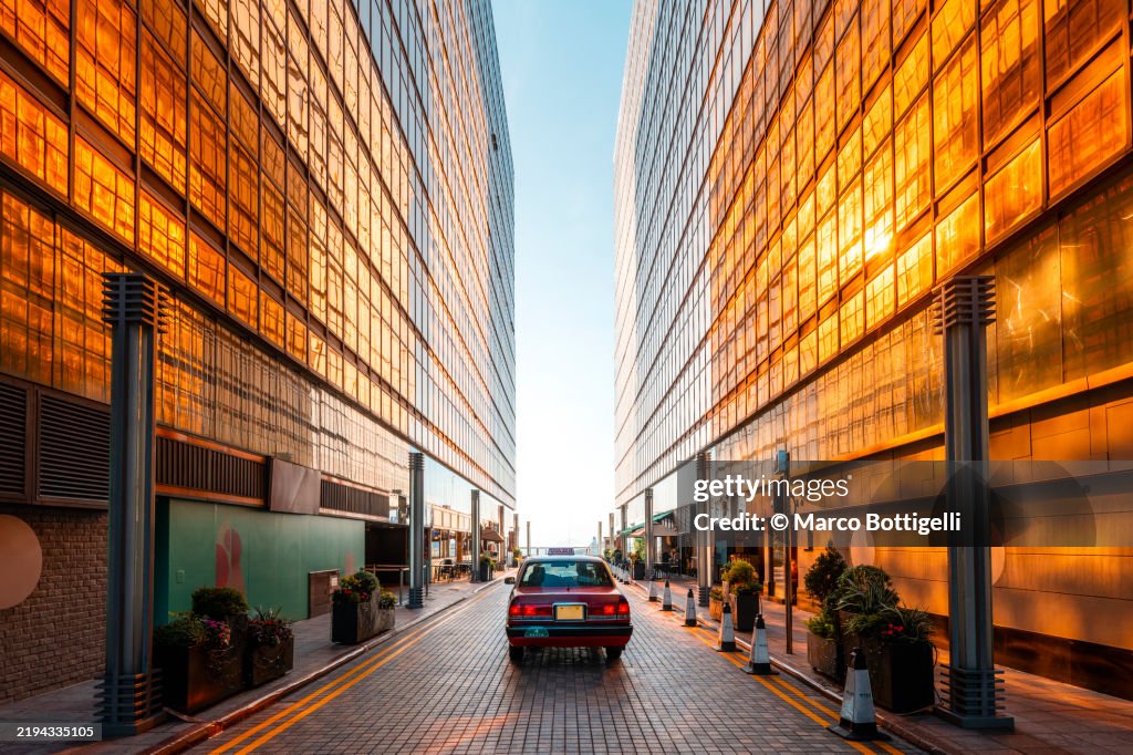 Taxi car driving among high rise buildings at sunset, Hong Kong