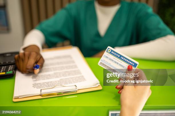 female patient holding health insurance card - zorgverzekering stockfoto's en -beelden