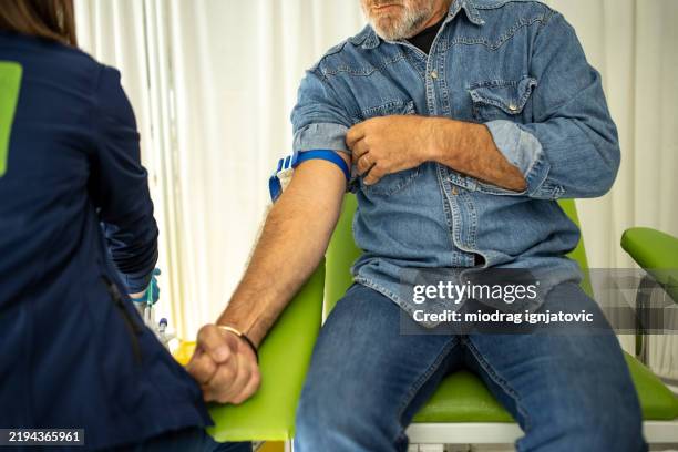 krankenschwester bereitet einen männlichen patienten auf eine blutspende vor - blutspende stock-fotos und bilder