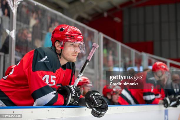 intense focus: ice hockey player leaning on the dasher board - ice hockey player stock pictures, royalty-free photos & images