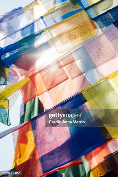 close up of tibetan prayer flags against the sky with the sun shining through it. - kathmandu nepal stock pictures, royalty-free photos & images