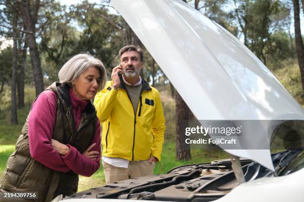 senior couple looking at broken car engine while calling for help - unexpected stock pictures, royalty-free photos & images