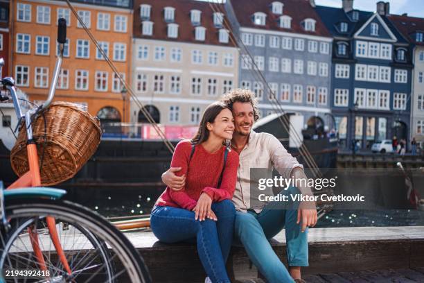 tourists relaxing in nyhavn, copenhagen, enjoying sunny day - copenhagen nyhavn stock pictures, royalty-free photos & images