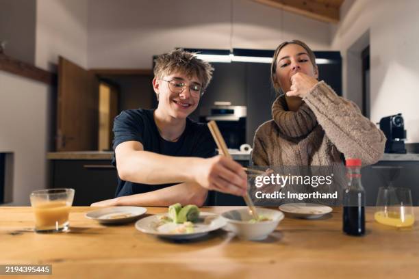 teenagers eating cucumber and salmon rolls in a modern kitchen - chopsticks stock pictures, royalty-free photos & images
