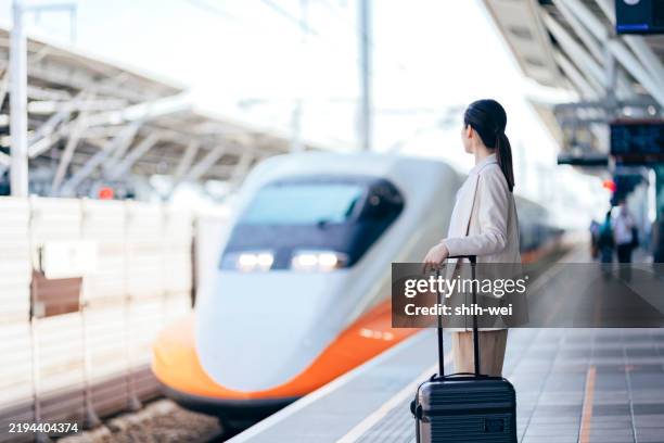 eine asiatische geschäftsfrau auf geschäftsreise wartet auf dem bahnsteig auf den zug - hochgeschwindigkeitszug stock-fotos und bilder