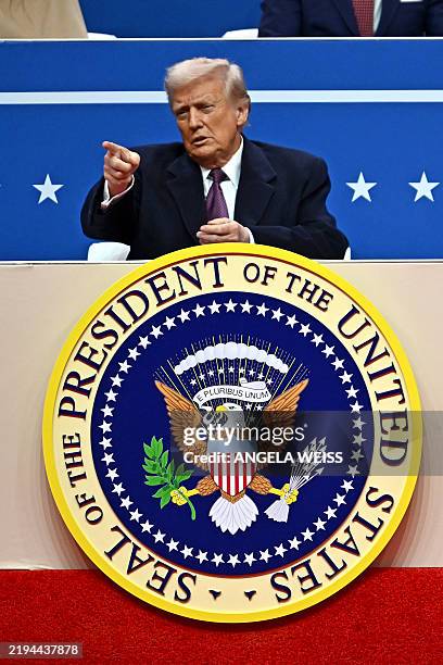 President Donald Trump gestures as he attends the inaugural parade inside Capital One Arena, in Washington, DC, on January 20, 2025.