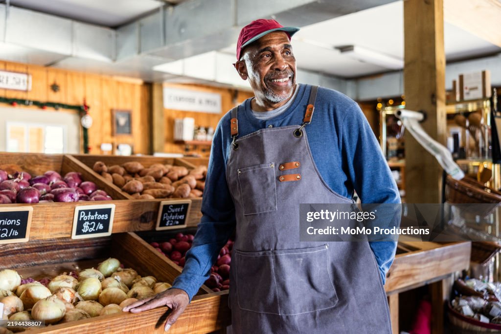Portrait of senior male market owner standing in front of vegetable stand