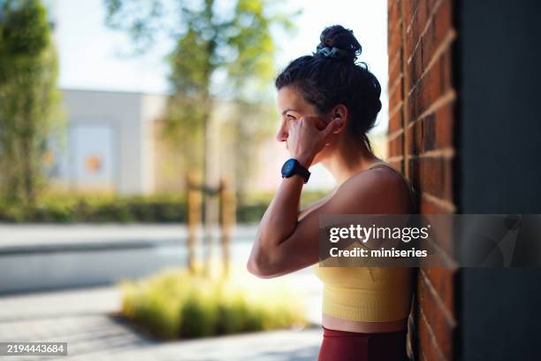 junge frau, die während einer entspannenden pause im freien musik hört - athleisure stock-fotos und bilder