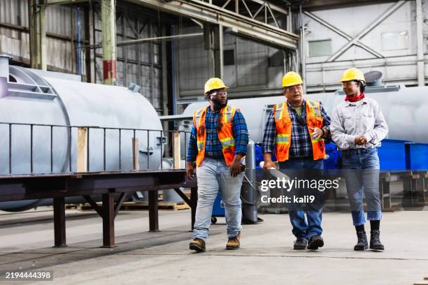 three workers conversing in steel fabrication factory - trabalhador manual imagens e fotografias de stock