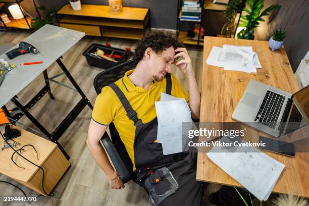 tired handyman sleeping at desk after work - handyman stock pictures, royalty-free photos & images