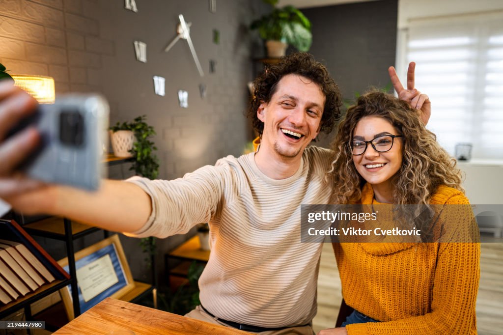 Cheerful couple taking a selfie at home, making funny faces
