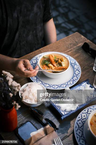 thai red curry with prawns served with steamed jasmine rice and prawn crackers on blue-patterned plates in a warm and rustic restaurant dining atmosphere - comida chinesa imagens e fotografias de stock