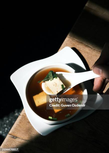 thai tofu soup with fresh herbs in a minimalist white bowl, highlighting traditional thai flavors and authentic culinary presentation at a thai restaurant - estilismo culinário imagens e fotografias de stock