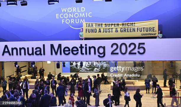 Members of Greenpeace, the environmentalist organization, hold a banner, written "Tax the super-rich! Fund a just and green future.", as a part of a...